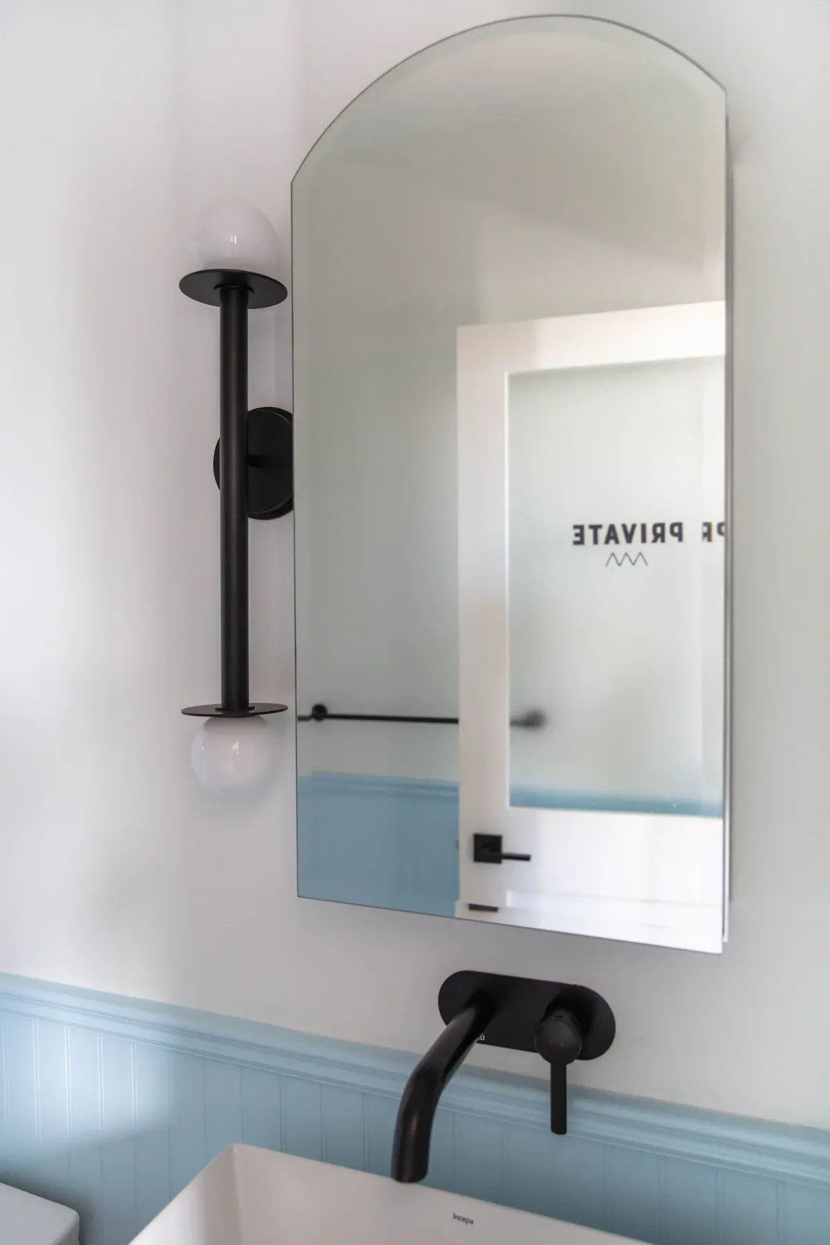 A bathroom mirror and black wall light above the sink