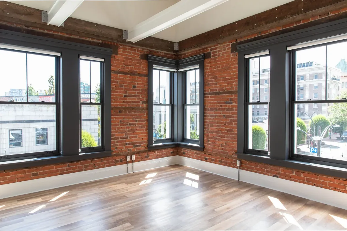 An empty room, brick walls and tall windows
