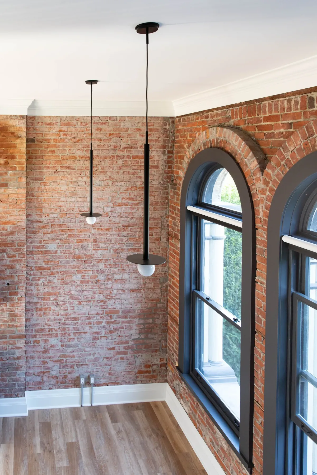 Two arched windows in a brick wall, pendants above