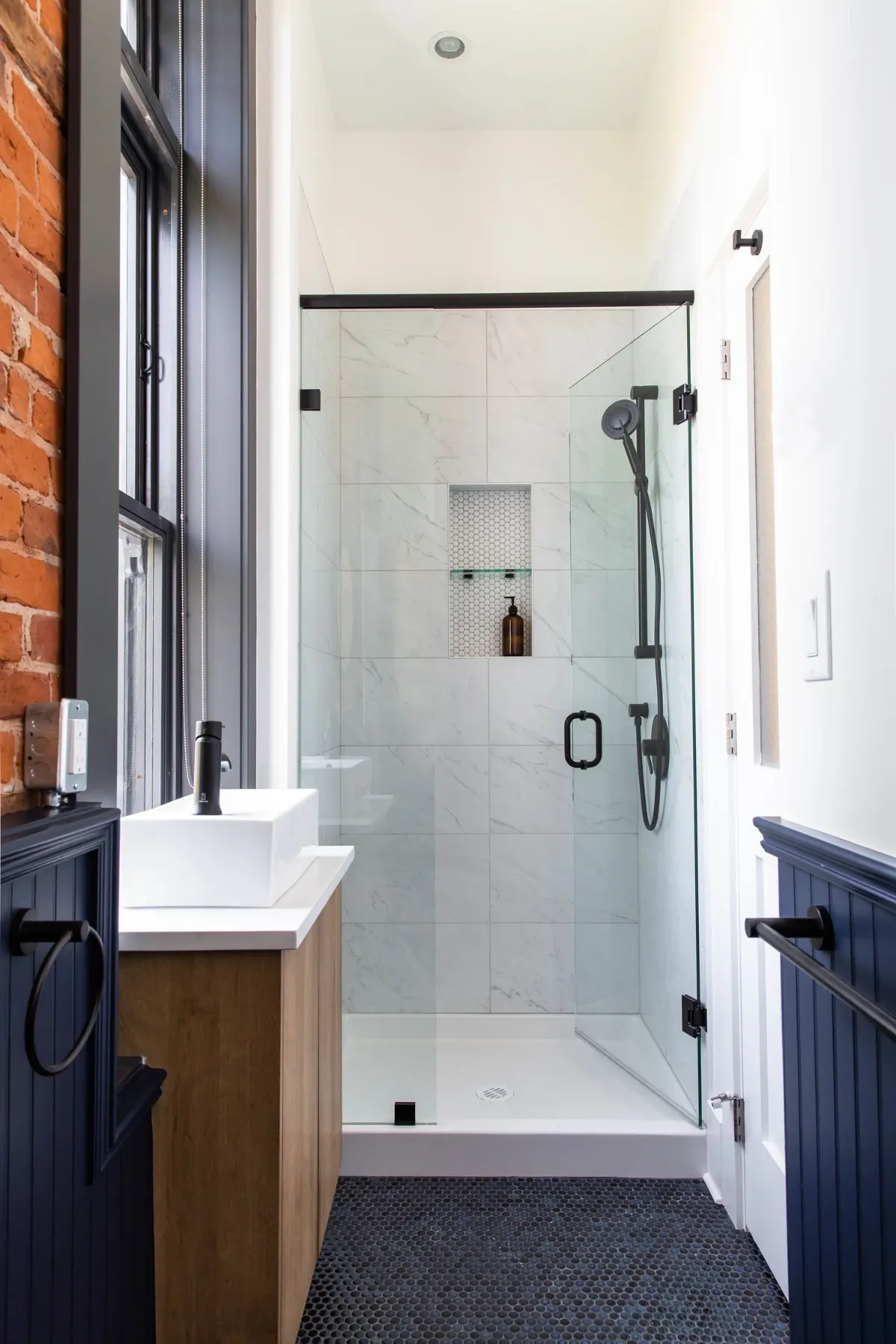 The shower in marble, the wood vanity beside it
