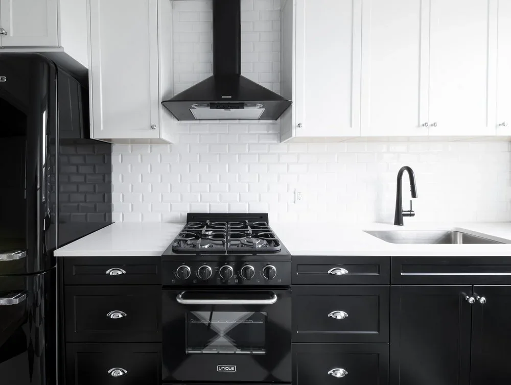 Kitchen on the Rigby floor, black cabinetry and a range under a hood