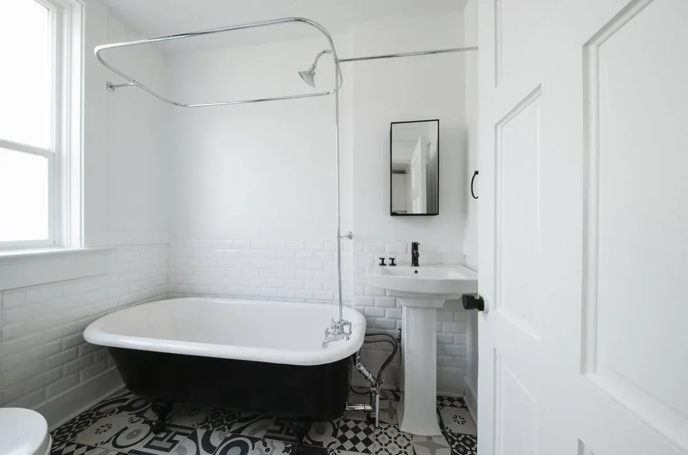 A claw foot bathtub on patterned tile, on the Rigby floor