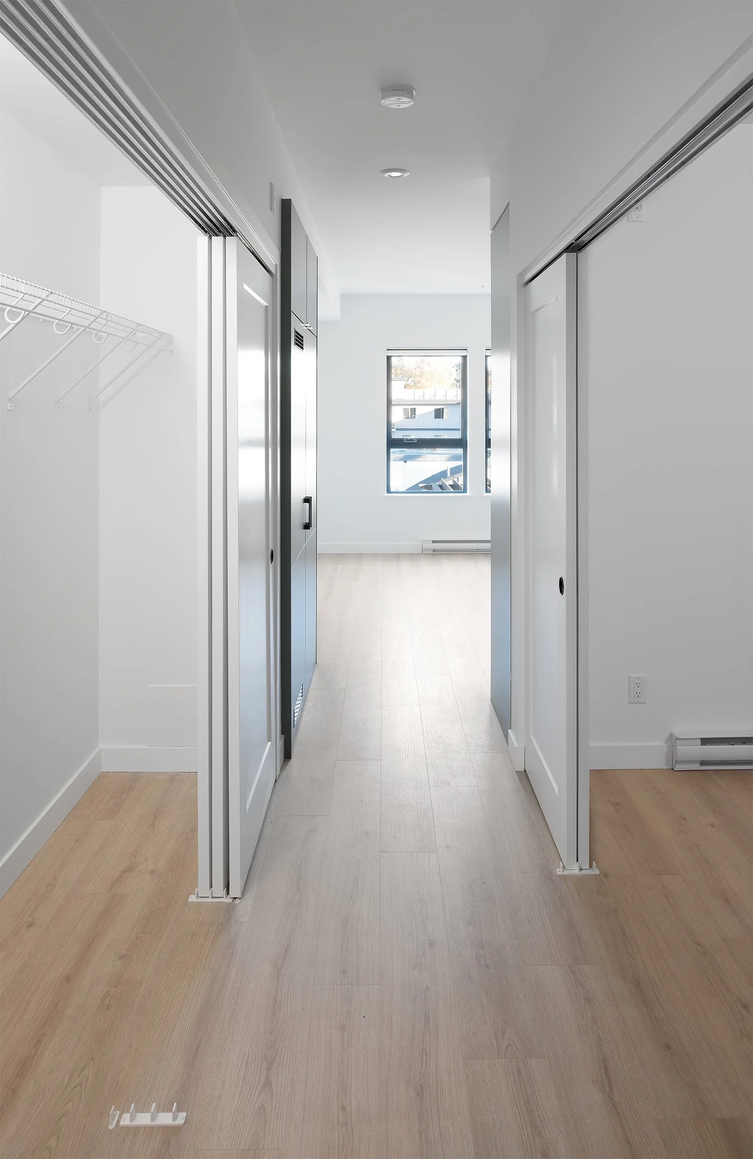 Entry hall with built-in closets, looking through to the living room windows