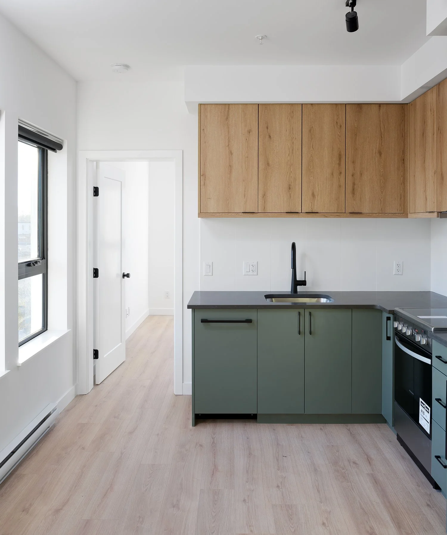Kitchen with green cabinetry and oak uppers, open to the living area