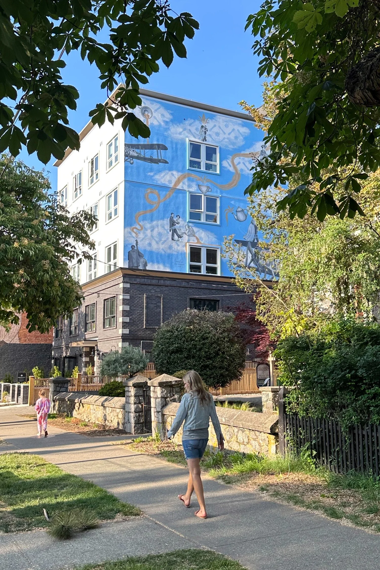 Two people walking past the Bell Apartments mural on Cook Street