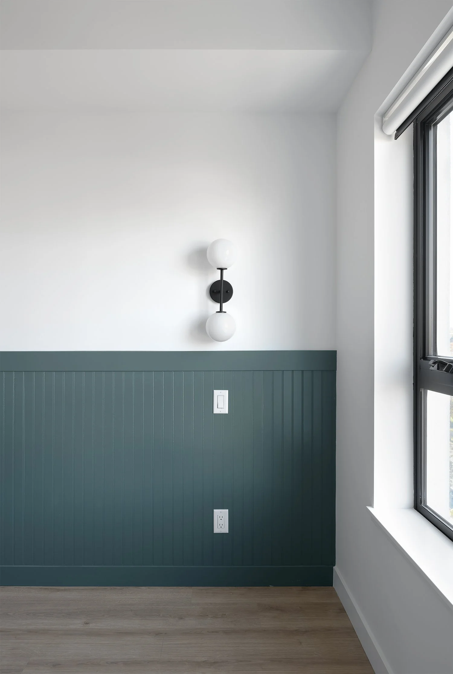 A wall sconce above deep green panelled wainscoting