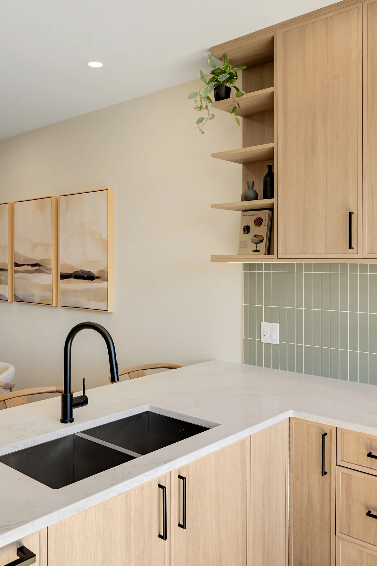 The kitchen sink and tap against the sage tile, open shelving above