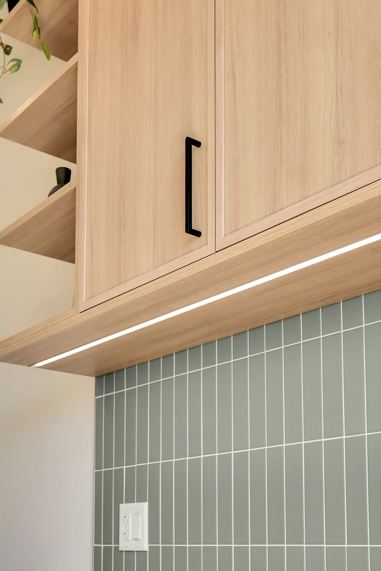 Under-cabinet lighting over the sage tile backsplash