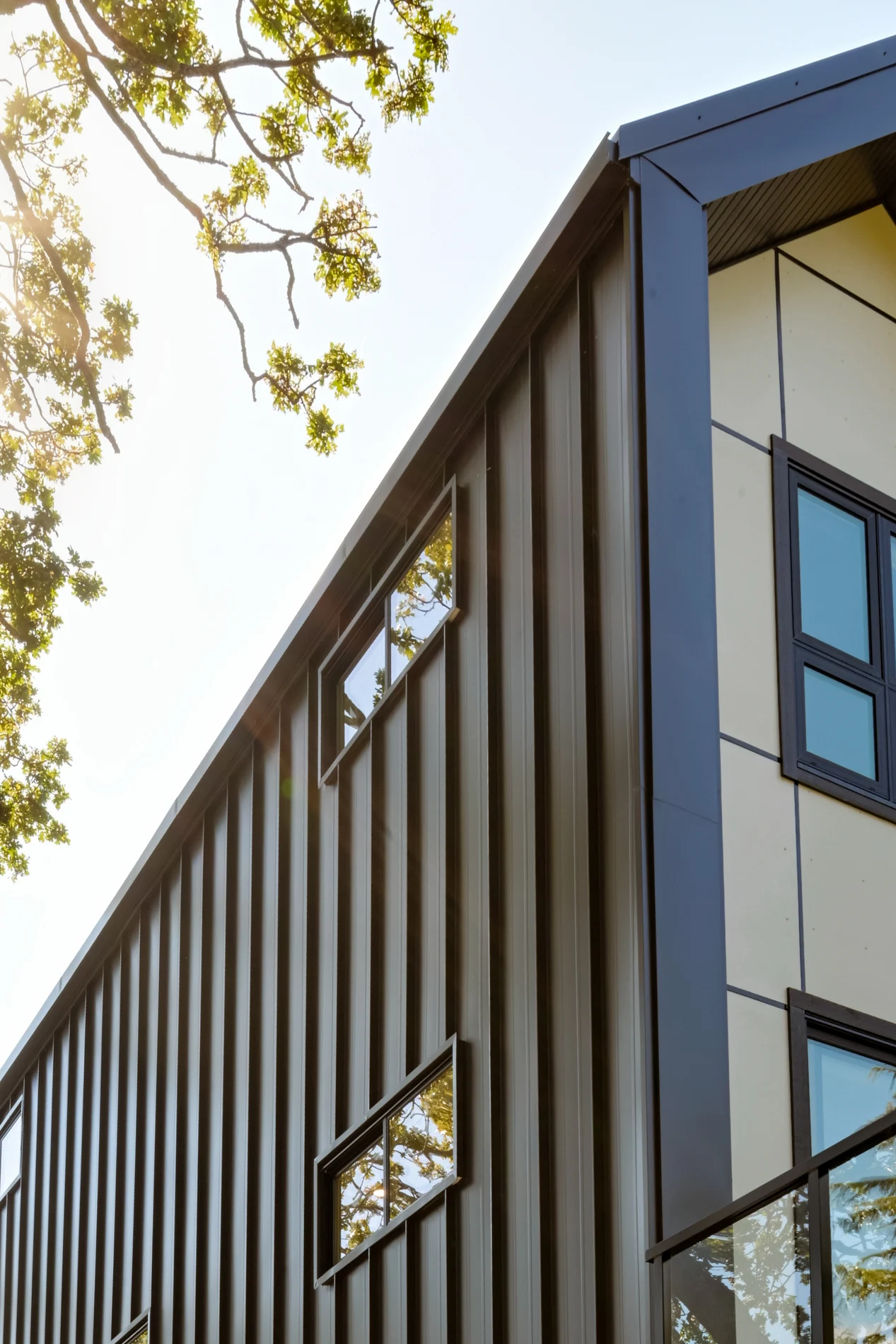 The standing-seam metal and panelled corner against the sky, backlit