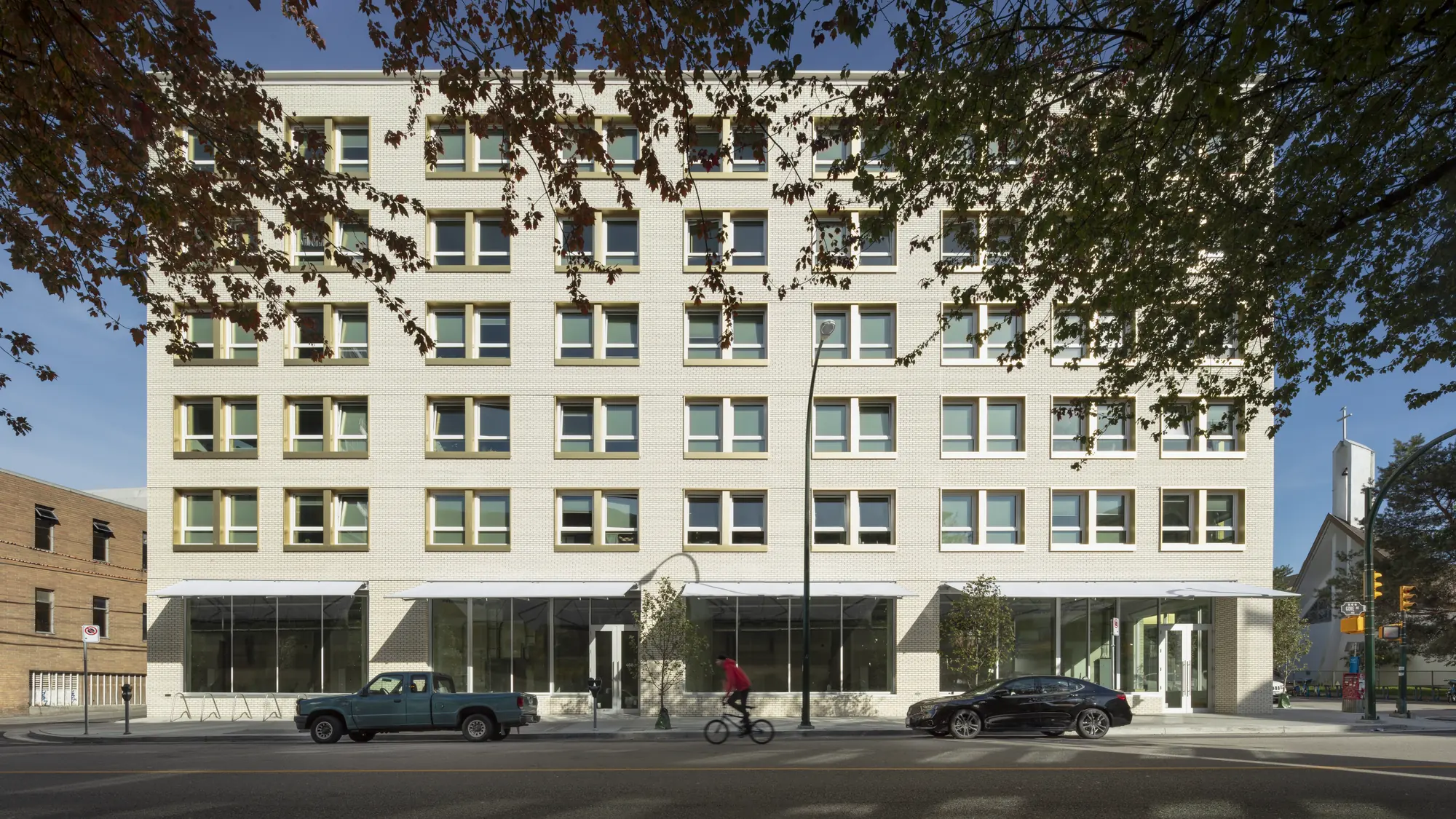 Brixton Flats, Vancouver — the white brick elevation behind autumn trees